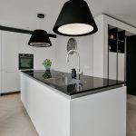 Strakke, moderne keuken in zwart met wit, met eiland en zwarte hanglampen